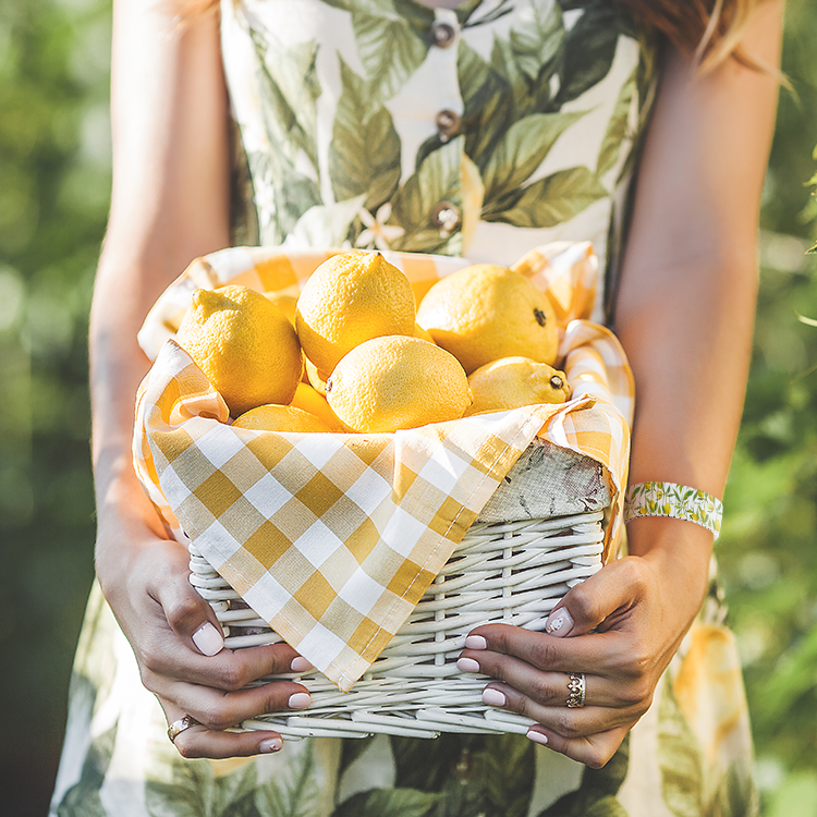 Frau trägt die Chocomoon Damenuhr Lemon beim Halten eines Zitronenkorbs – sommerliches, frisches Motiv