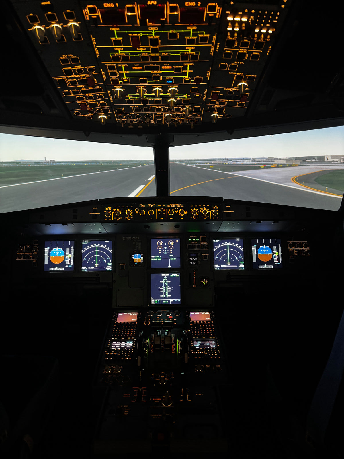 Pohled zepředu na kokpit simulátoru letadla Airbus A321XLR s osvětleným stropním panelem