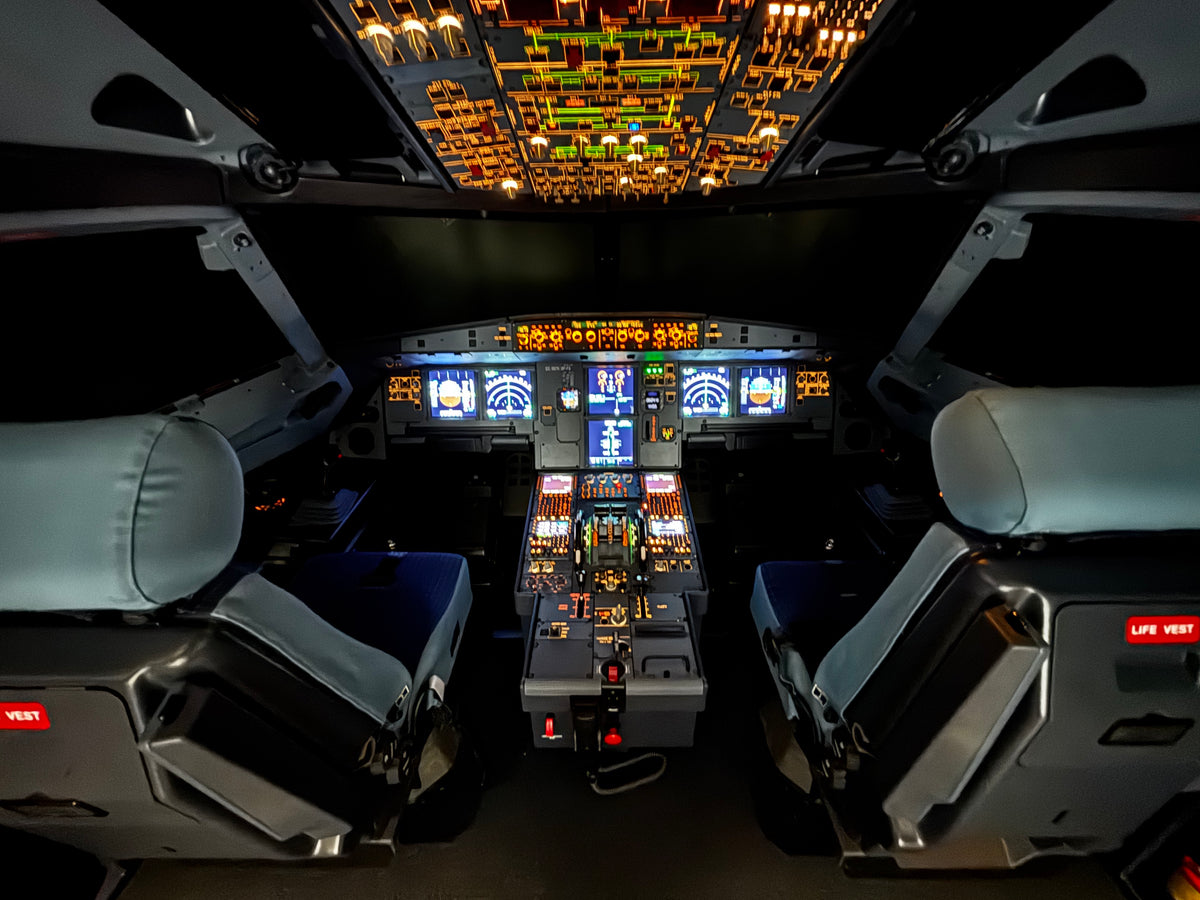 Celkový pohled na kokpit simulátoru letadla Airbus A321XLR s pilotními sedadly a přístroji